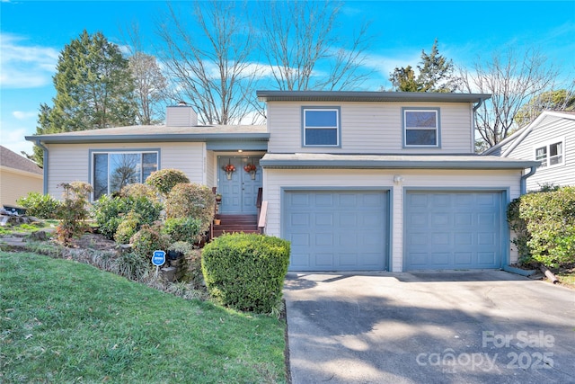 split level home with a garage, concrete driveway, a front lawn, and a chimney