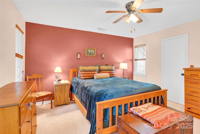 bedroom with ceiling fan, visible vents, and light colored carpet