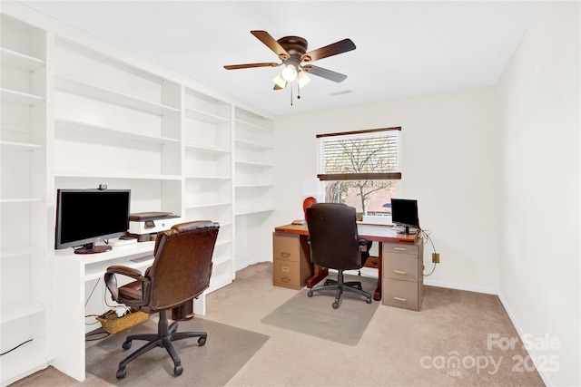 carpeted office space featuring baseboards and a ceiling fan