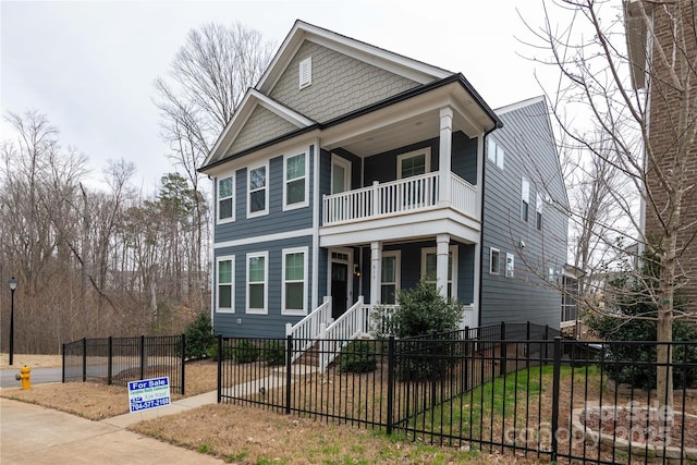 view of front of house featuring covered porch, a fenced front yard, and a balcony