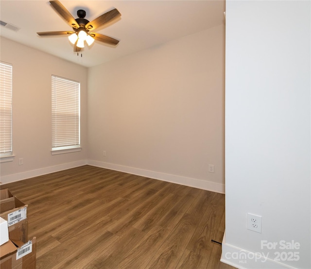 spare room featuring dark wood-style floors, visible vents, baseboards, and a ceiling fan