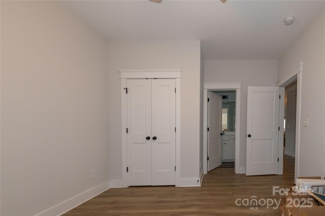 unfurnished bedroom featuring a closet, baseboards, and wood finished floors