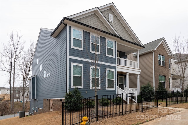 view of front of house featuring a fenced front yard, a balcony, and central air condition unit