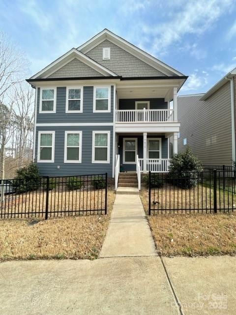 view of front of home featuring a porch, a balcony, and a fenced front yard