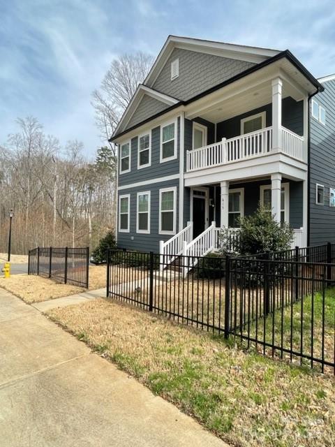 view of front of home featuring a fenced front yard, covered porch, and a balcony