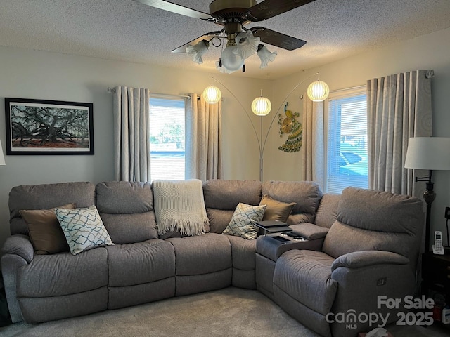 living area featuring carpet flooring, plenty of natural light, a textured ceiling, and a ceiling fan