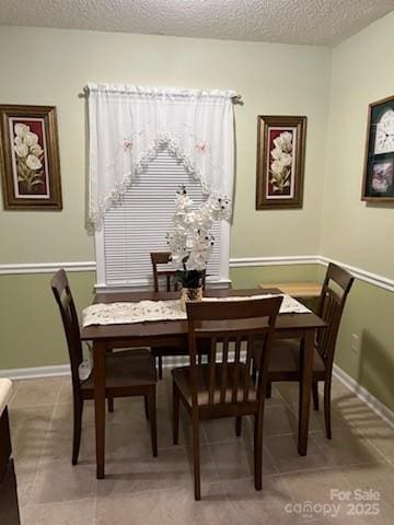 dining room featuring a textured ceiling and baseboards