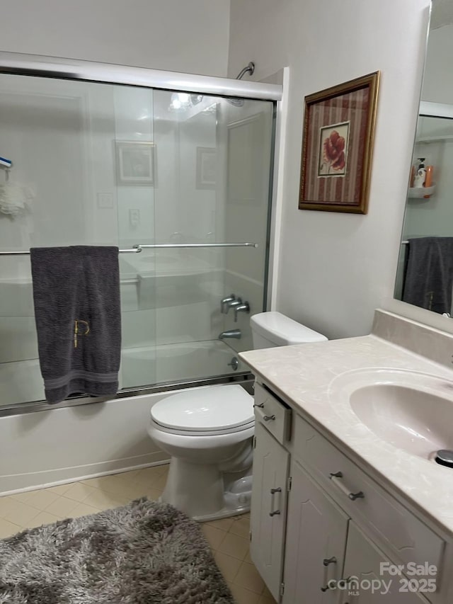 bathroom featuring tile patterned floors, toilet, vanity, and shower / bath combination with glass door