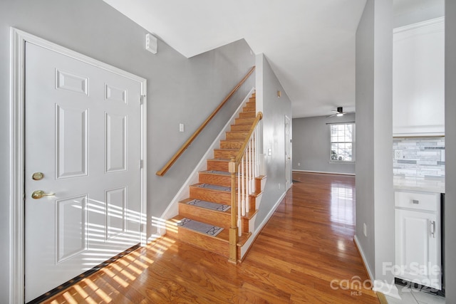 staircase with ceiling fan, baseboards, and wood finished floors