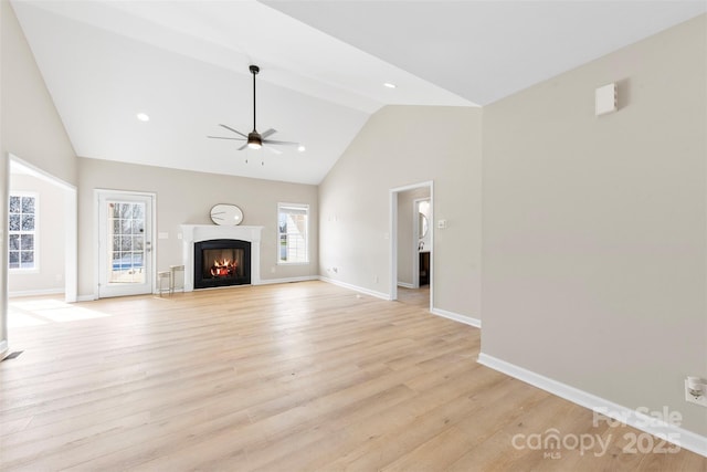 unfurnished living room with baseboards, ceiling fan, a lit fireplace, recessed lighting, and light wood-style flooring