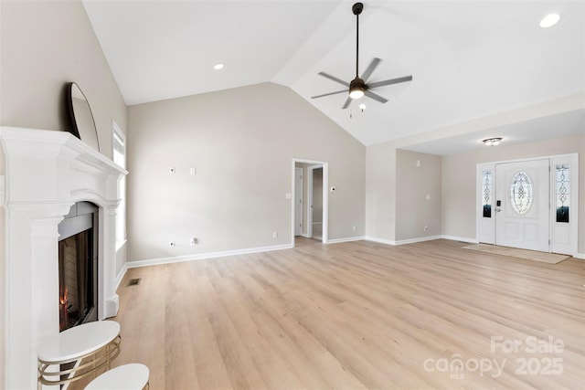 unfurnished living room featuring visible vents, light wood-style flooring, a lit fireplace, baseboards, and ceiling fan