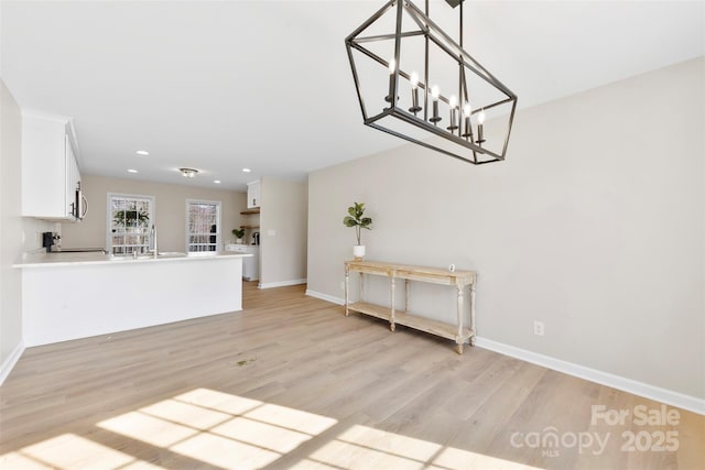 unfurnished living room featuring recessed lighting, baseboards, an inviting chandelier, and light wood finished floors