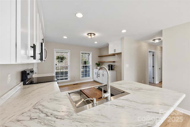 kitchen with a sink, light stone counters, white cabinetry, recessed lighting, and appliances with stainless steel finishes