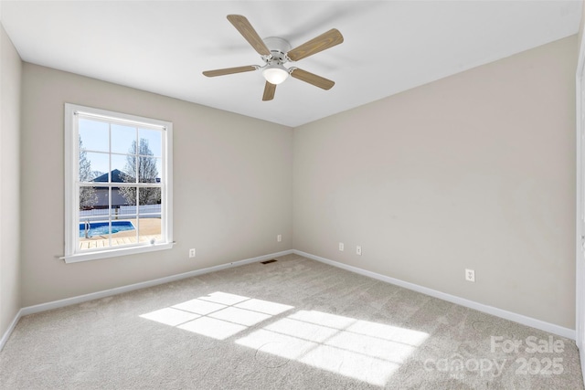 empty room with visible vents, baseboards, a ceiling fan, and carpet flooring