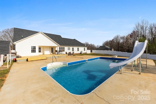 view of swimming pool featuring a fenced in pool, a water slide, a wooden deck, a fenced backyard, and a patio area