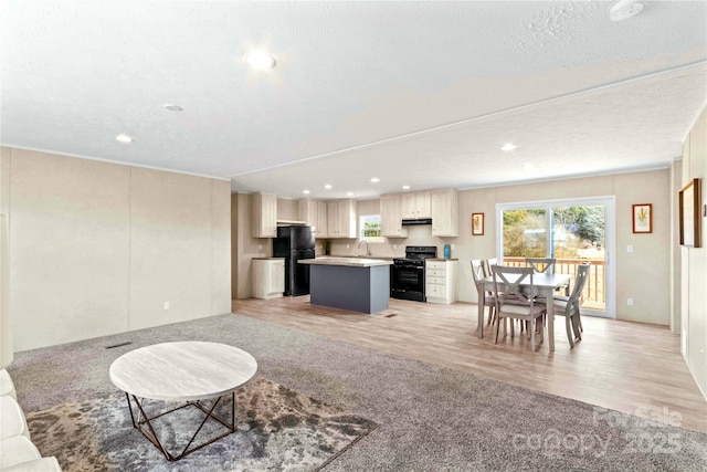 living area with light wood-type flooring, a textured ceiling, and recessed lighting