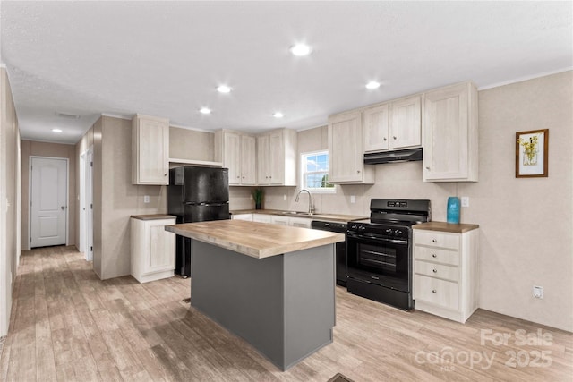 kitchen with light wood-style flooring, butcher block counters, under cabinet range hood, and black appliances