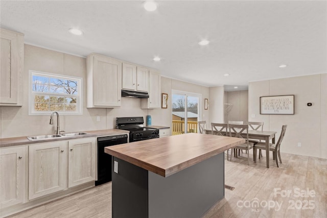 kitchen featuring light wood-style flooring, under cabinet range hood, butcher block countertops, a sink, and black appliances