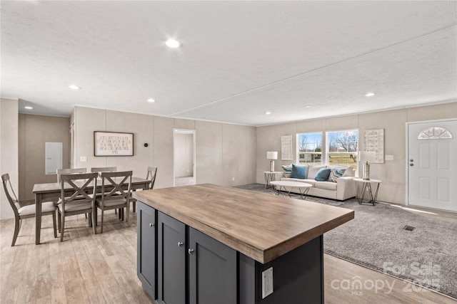 kitchen with light wood finished floors, a kitchen island, open floor plan, wooden counters, and recessed lighting