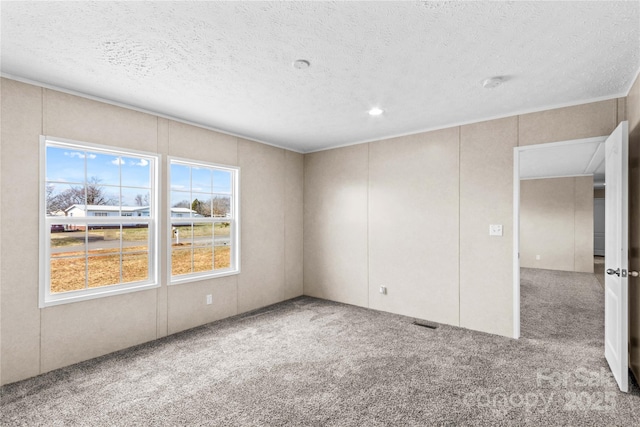 carpeted spare room featuring a textured ceiling and visible vents