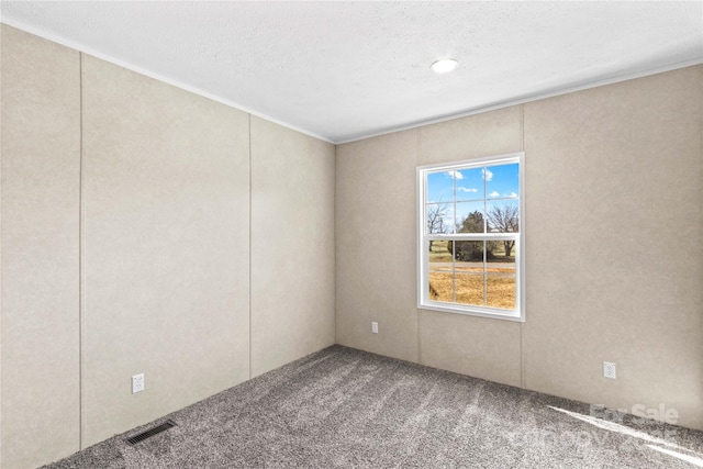 unfurnished room with a textured ceiling, visible vents, and carpet flooring