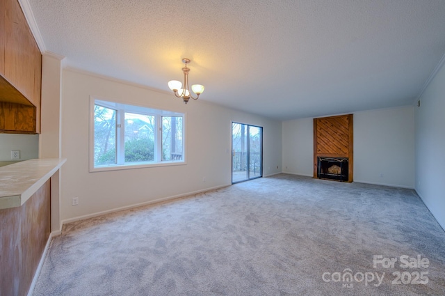 unfurnished living room with a textured ceiling, crown molding, light carpet, a notable chandelier, and a large fireplace