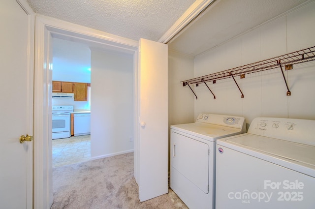 washroom featuring light colored carpet, washing machine and dryer, and a textured ceiling