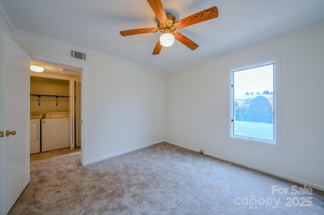 unfurnished bedroom with visible vents, baseboards, ornamental molding, carpet floors, and separate washer and dryer