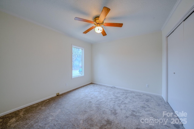 unfurnished bedroom with carpet, baseboards, ornamental molding, a closet, and a textured ceiling