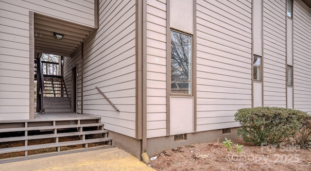 view of side of home with crawl space and stairway