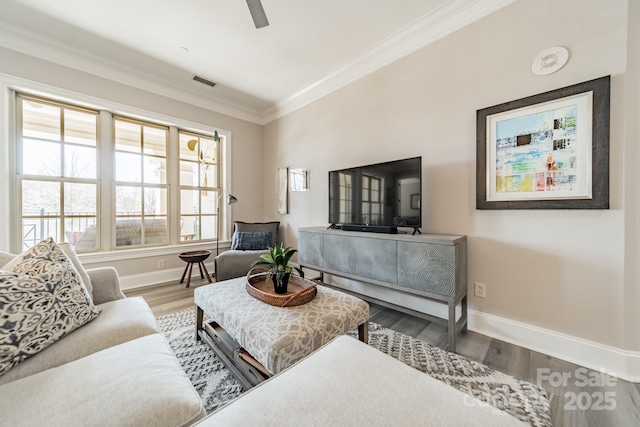 living area featuring visible vents, baseboards, wood finished floors, and ornamental molding