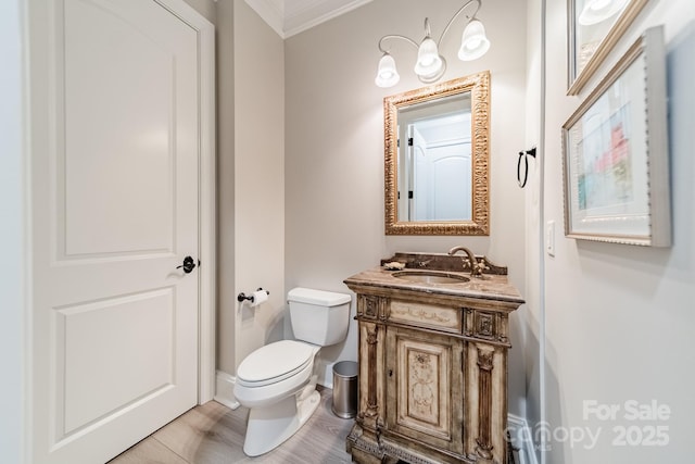 bathroom with baseboards, toilet, ornamental molding, and vanity