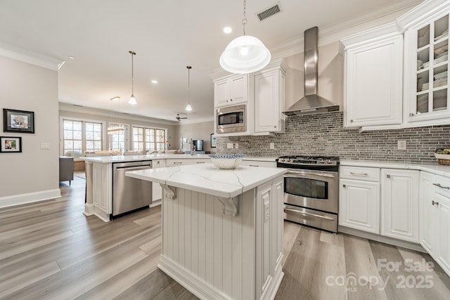 kitchen with visible vents, a peninsula, stainless steel appliances, wall chimney exhaust hood, and backsplash