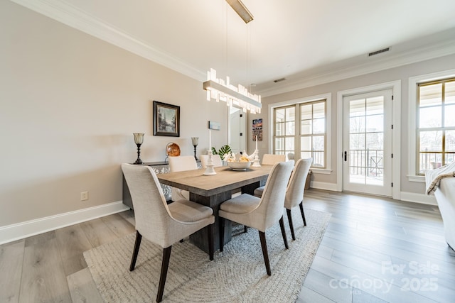 dining room featuring visible vents, plenty of natural light, wood finished floors, and ornamental molding