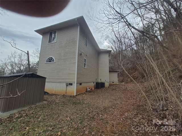 view of home's exterior with crawl space, a shed, central AC unit, and an outbuilding