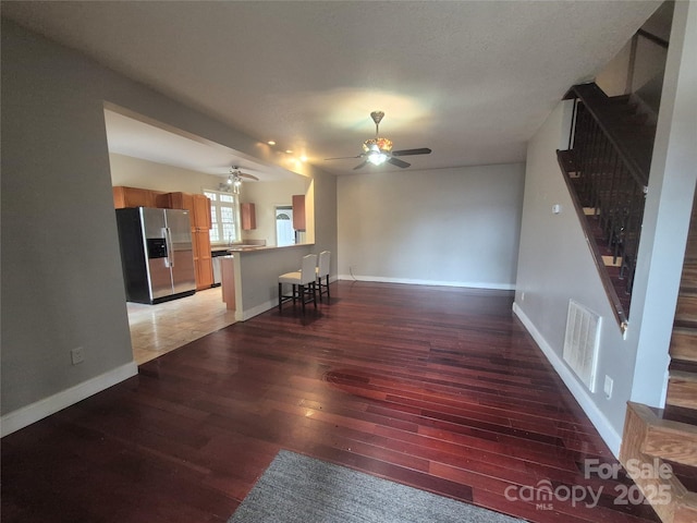 unfurnished living room with stairway, baseboards, visible vents, and light wood finished floors