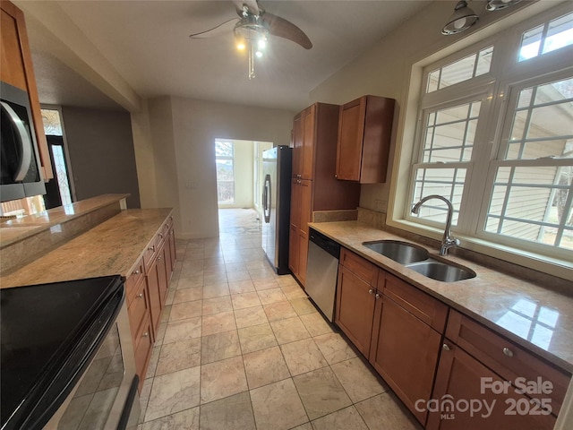 kitchen with brown cabinets, light countertops, appliances with stainless steel finishes, a ceiling fan, and a sink