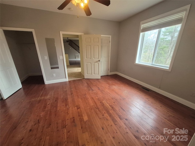 unfurnished bedroom featuring a ceiling fan, baseboards, visible vents, and dark wood-type flooring