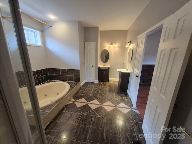 full bath with a whirlpool tub, baseboards, and vanity