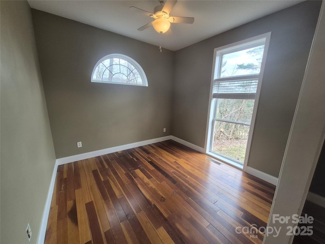 unfurnished room with dark wood-type flooring, visible vents, and baseboards