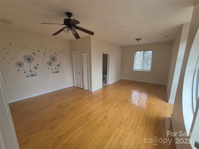 unfurnished room featuring light wood-type flooring, baseboards, and a ceiling fan