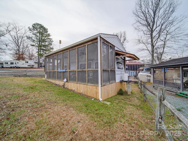 view of property exterior with a yard and a sunroom