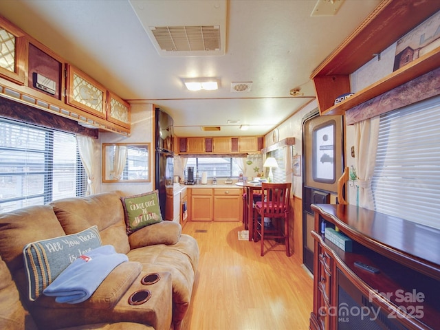 living area with plenty of natural light, light wood-style flooring, and visible vents