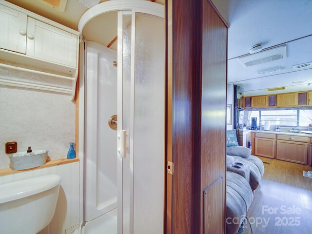 bathroom with walk in shower, wood finished floors, and toilet