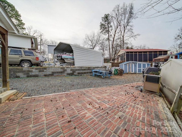 view of patio / terrace with a carport, an outdoor structure, and a storage shed