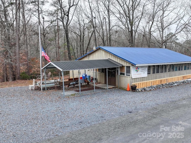 view of front of property with gravel driveway, metal roof, and a carport