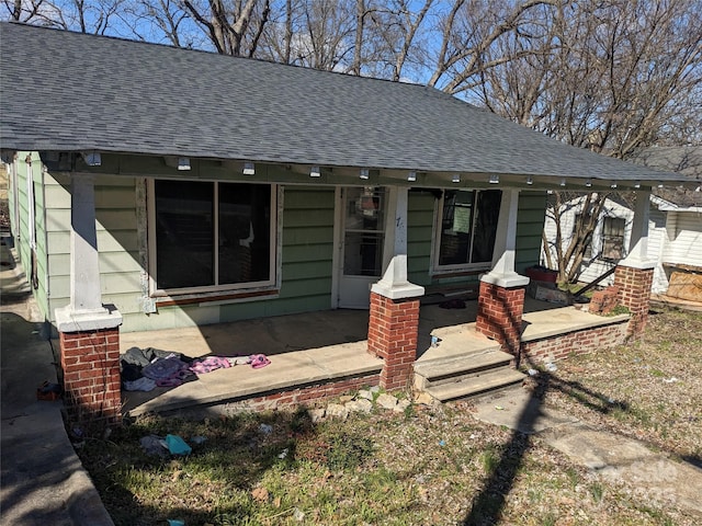 bungalow-style home with a shingled roof and a porch