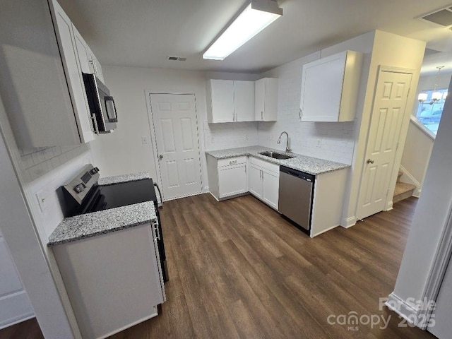 kitchen featuring dark wood finished floors, visible vents, appliances with stainless steel finishes, white cabinetry, and a sink