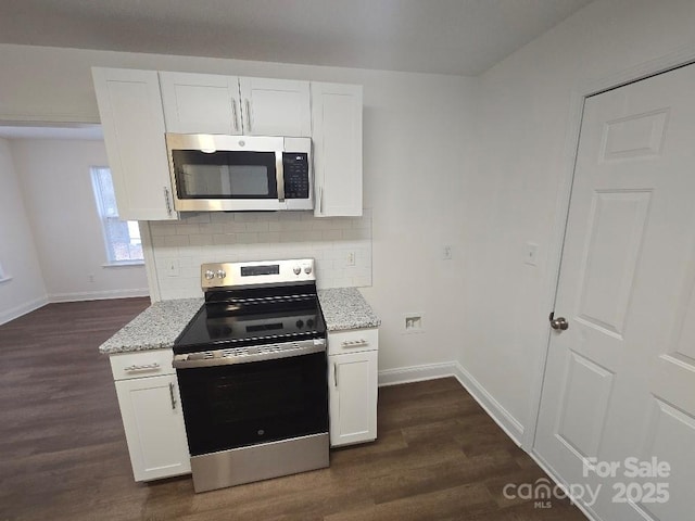kitchen featuring appliances with stainless steel finishes, dark wood-style flooring, and light stone countertops