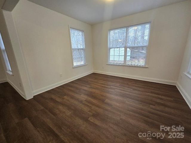 spare room featuring dark wood-style floors and baseboards